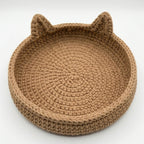 A round, hand-crocheted basket with cat ears on the rim, shown on a clean white background.