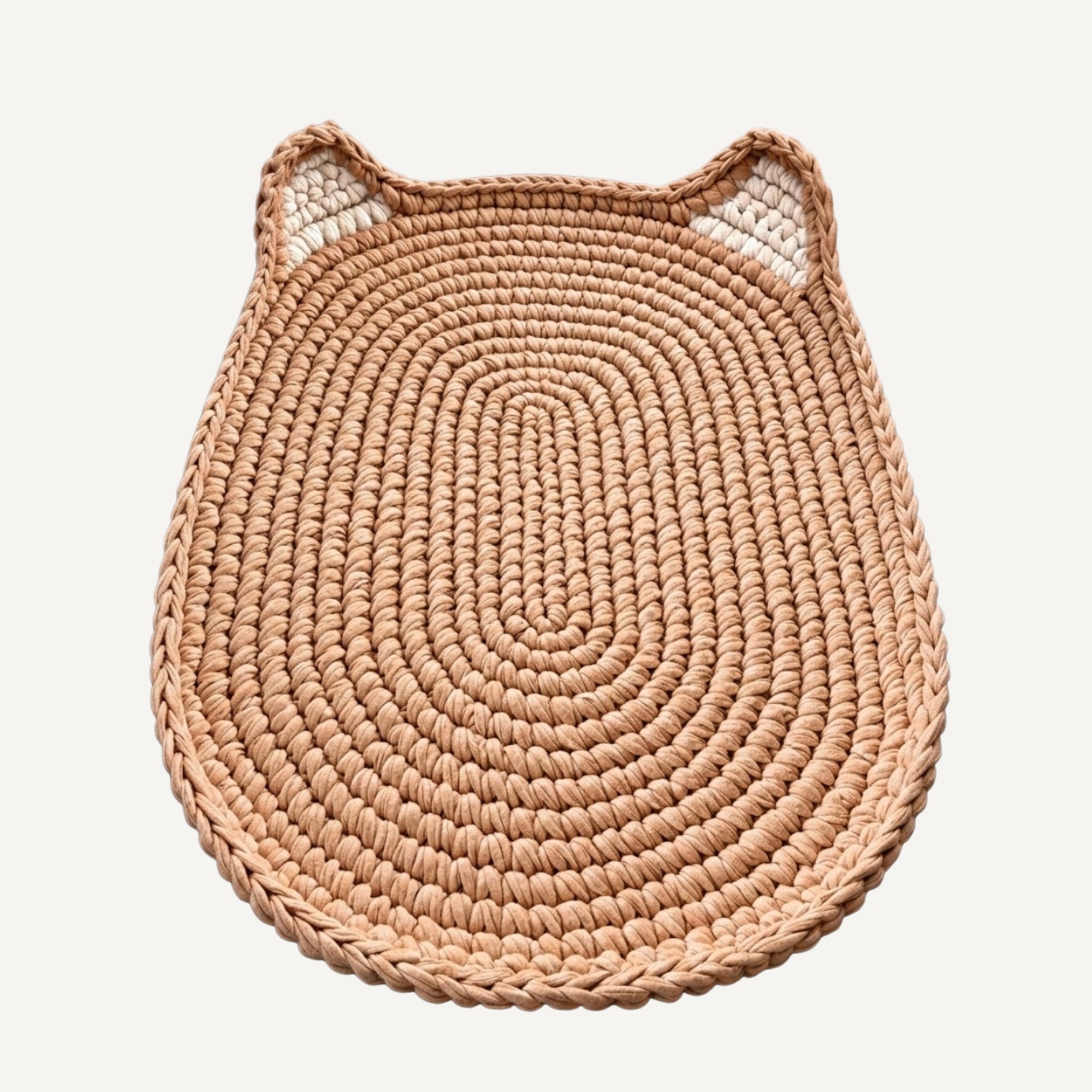 A round woven mat with cat-ear details on top, crafted from natural tan raffia or seagrass, shown on a light off-white background.